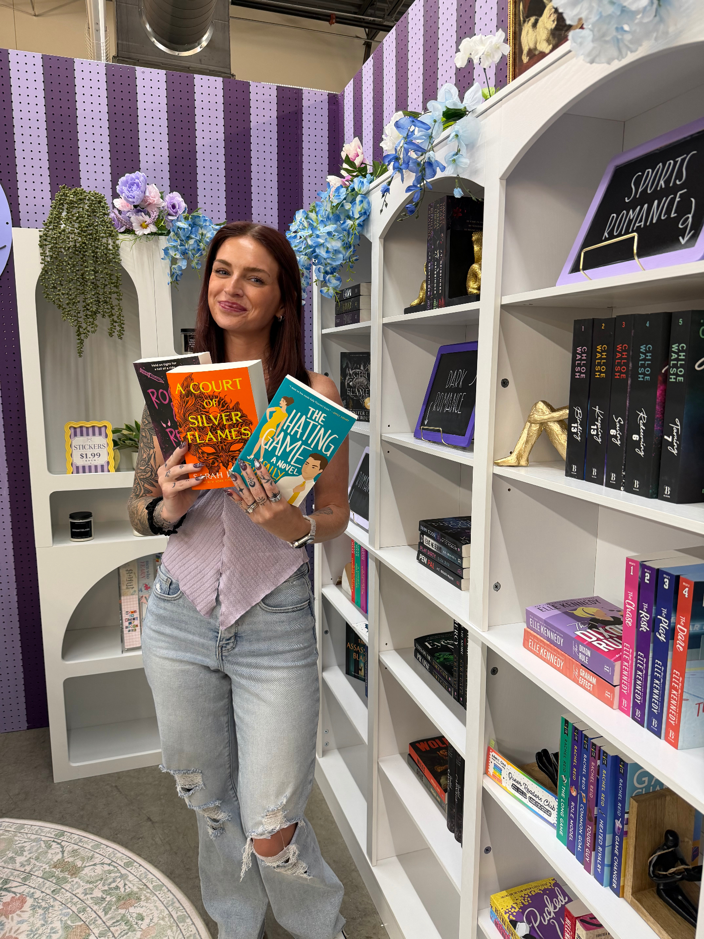 Aislin holding romance books in the Turn A. Paige booth